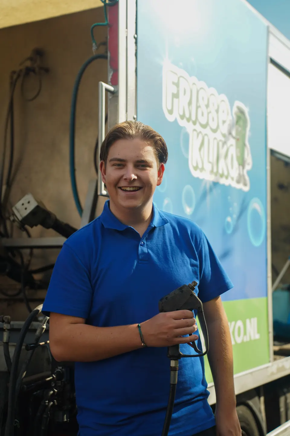 Medewerker in Frisse Kliko-polo naast de bestickerde reinigingswagen.