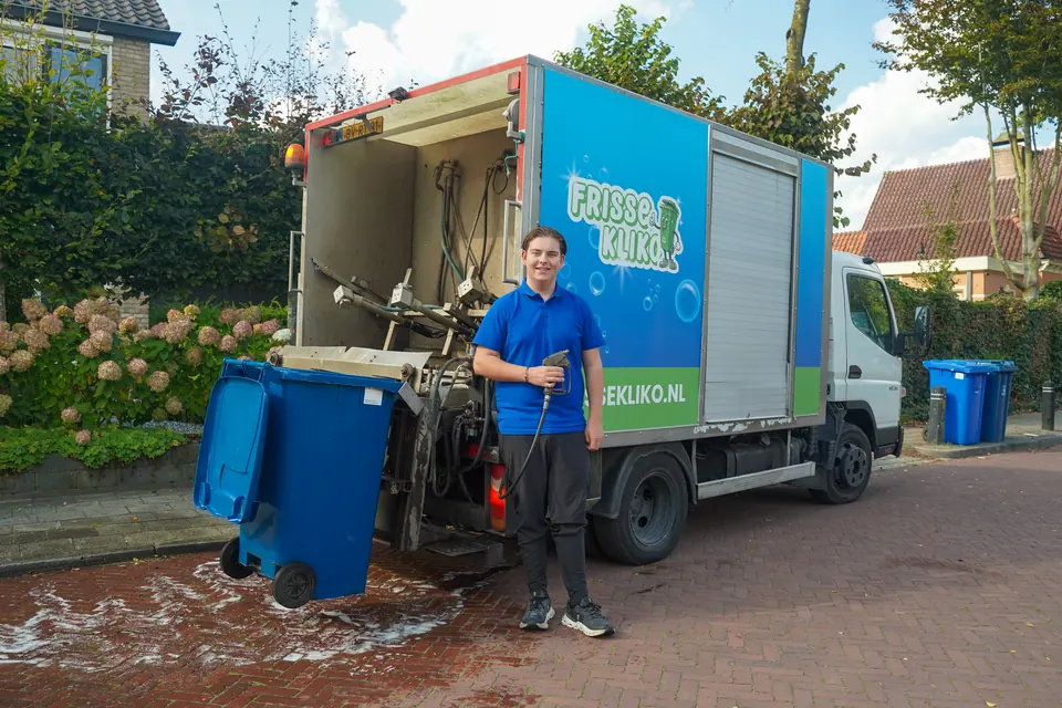 Medewerker van Frisse Kliko naast de reinigingswagen en een blauwe container.